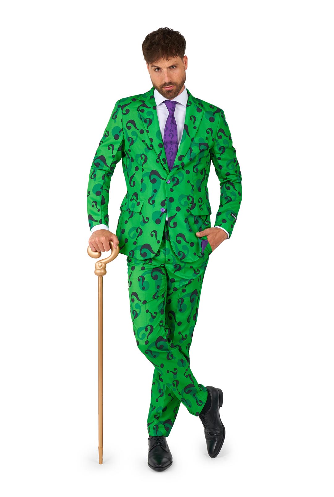 Wearing The Riddler costume by Suitmeister, a man stands in a green suit adorned with black question marks. He holds a gold cane and sports a purple tie and black shoes, with one hand casually placed in his pocket against a white background.