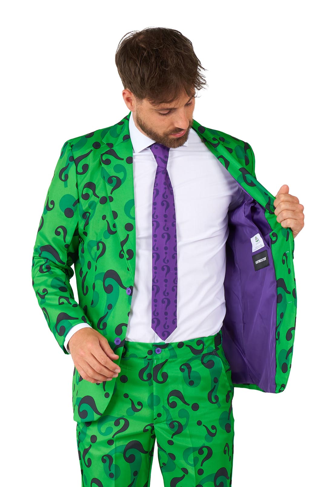 A man dressed in The Riddler costume by Suitmeister opens his jacket, revealing a vibrant purple lining. The suit is a striking green with black question marks, and he complements it with a white shirt and purple tie as he looks downward at the lining.