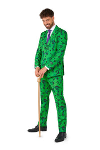 A man dressed in Suitmeister's The Riddler suit, featuring a green ensemble adorned with black question marks, a white shirt, and a purple tie, while holding a gold cane. He is smiling confidently against a white background.