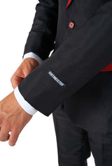 A person adjusting the sleeve of a black Harry Potter Gryffindor™ Suit by Suitmeister, with the brand name embroidered near the cuff. The suit features red accents, and the person's hand is visible as they hold the jacket sleeve.