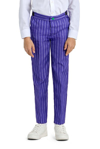 A child is dressed in The Joker costume from Suitmeister, featuring a white shirt and purple pants with white vertical stripes. They stand with their hands by their sides, wearing white sneakers, and the pants are fastened with a green button.