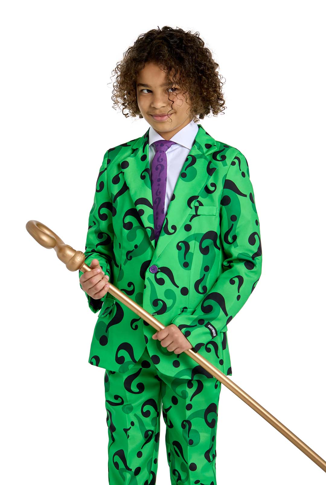 The child is dressed as "The Riddler costume" by Suitmeister, featuring a bright green suit adorned with black question marks, complemented by a white shirt and purple tie. They are holding a long gold staff and smiling slightly against a plain white background.