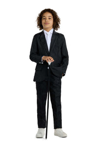 A child with curly hair is wearing the Suitmeister Gangster Pinstripe Black suit and white sneakers. They are standing confidently, holding a black walking cane, against a white background.