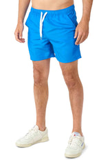 The image features an individual sporting the Batman™ - summer set by Suitmeister, highlighted by vibrant blue shorts with a white drawstring, paired with sleek white sneakers. The photo is cropped from the waist down, showcasing a relaxed and summery ensemble.