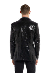 The image features an individual wearing the Sequins blazer Black jacket by Suitmeister, seen from behind. The jacket sparkles and reflects light, complemented by black pants against a plain white background.