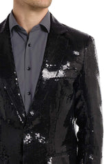 A person dressed in Suitmeister's Sequin Blazer Black over a dark gray button-up shirt. The image emphasizes the upper body, showcasing the textured pattern and sparkle of the fabric.