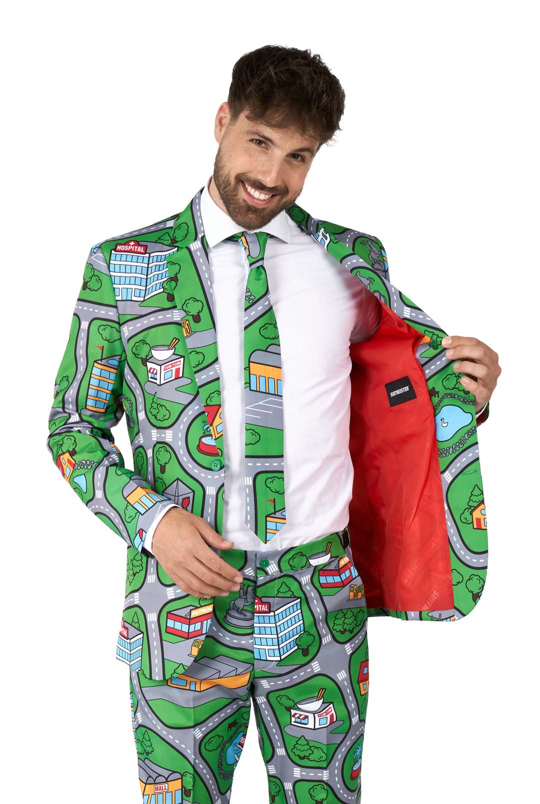 A man smiles while wearing the Suitmeister Carpet City Green - Play Carpet suit, which showcases a playful town map design with roads, buildings, and hearts. He opens the jacket to reveal its bright red lining.