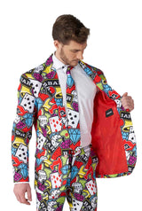 A man dressed in the Suitmeister's Casino Icons suit, featuring a lively casino theme with poker chips, dice, cards, and BAR symbols, reveals the red interior of his jacket.