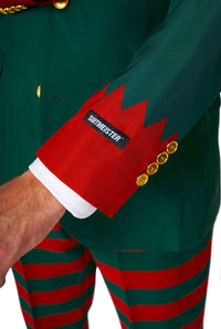 A close-up of a person wearing the Santa's Elf Green suit from Suitmeister, featuring festive gold buttons on the sleeve with a Suitmeister label. The matching pants showcase red and green stripes, complemented by red zigzag cuffs.