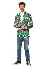 A person is wearing the Christmas Green Nordic Jacket by Suitmeister, a vibrant Christmas-themed blazer adorned with snowflakes, trees, and ornaments. They pair it with a white shirt, blue jeans, and black sneakers while standing against a plain white background.