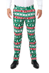 A person is dressed in the Suitmeister Christmas Green Nordic suit, which showcases a festive pattern of green, red, and white colors adorned with snowflakes, Christmas trees, ornaments, and reindeer. They complete their ensemble with black shoes and a white shirt.