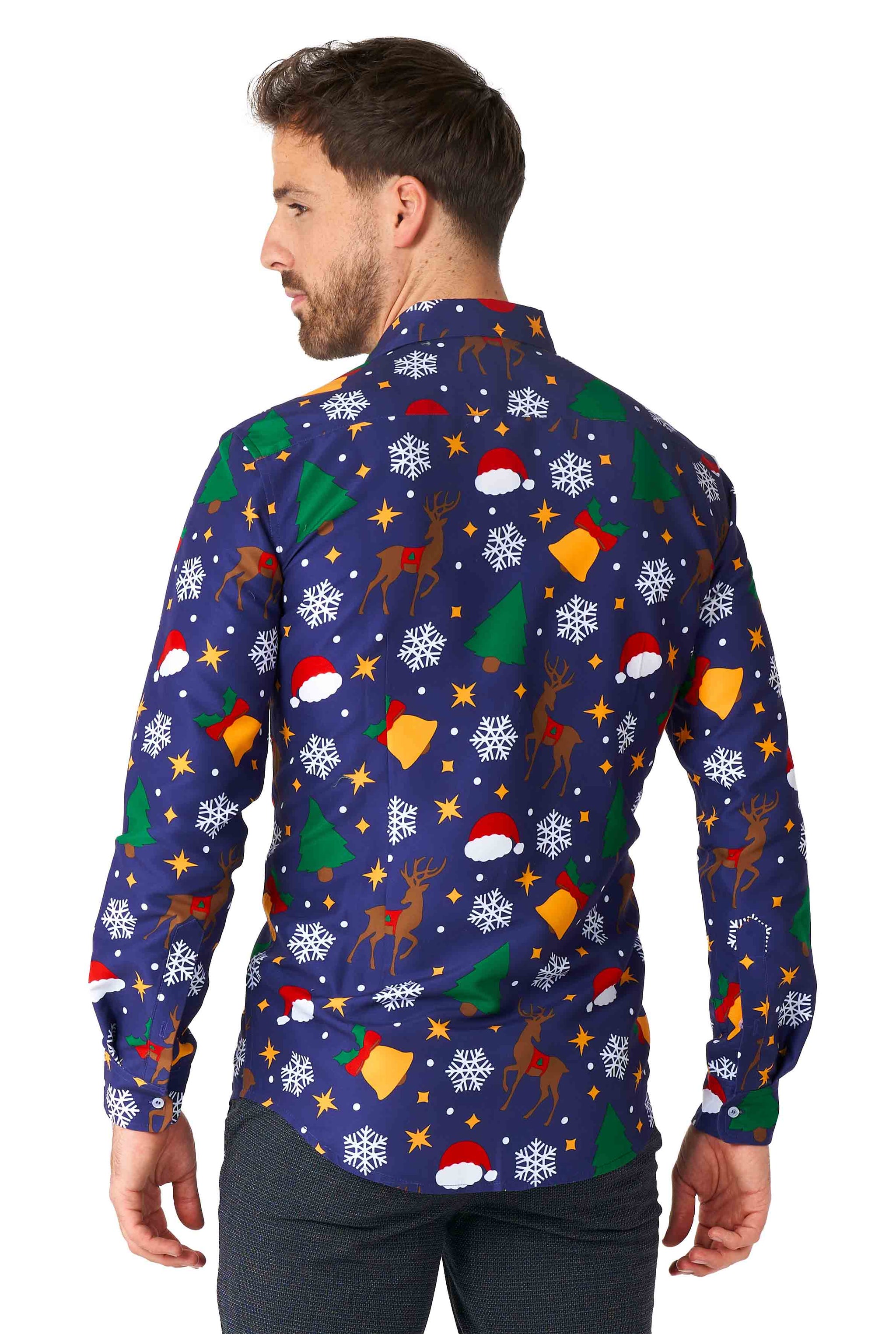 A person with short dark hair is wearing the Suitmeister Christmas Icons Blue shirt, which features a festive array of Christmas-themed prints such as reindeer, snowflakes, stars, and Santa hats on a dark blue background. The person is viewed from the back and slightly turned to the side.