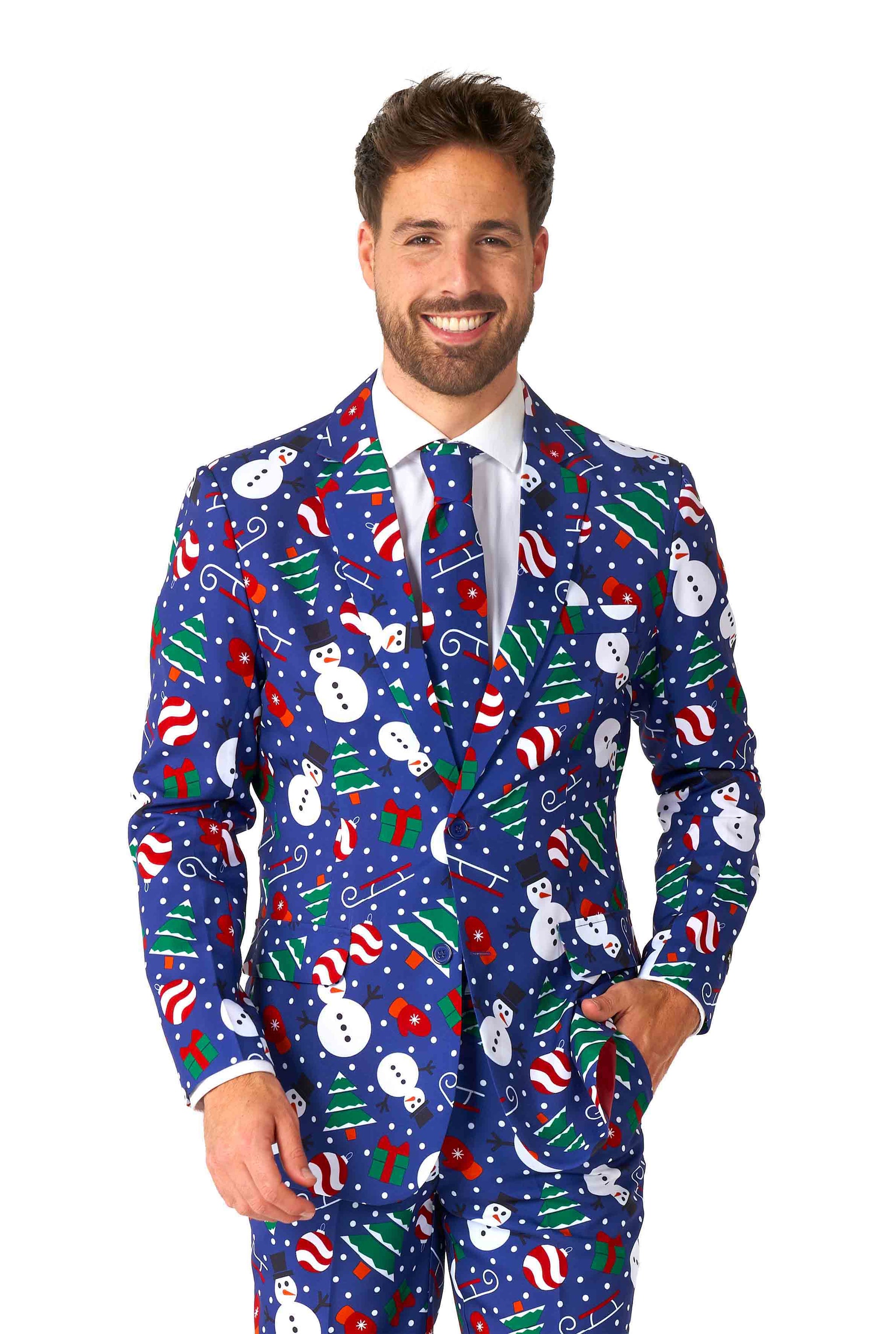 A man wearing the Suitmeister Christmas Snowman Blue suit, set against a blue background adorned with snowmen, candy canes, and holiday ornaments. He is smiling and has on a light blue shirt paired with a matching tie.