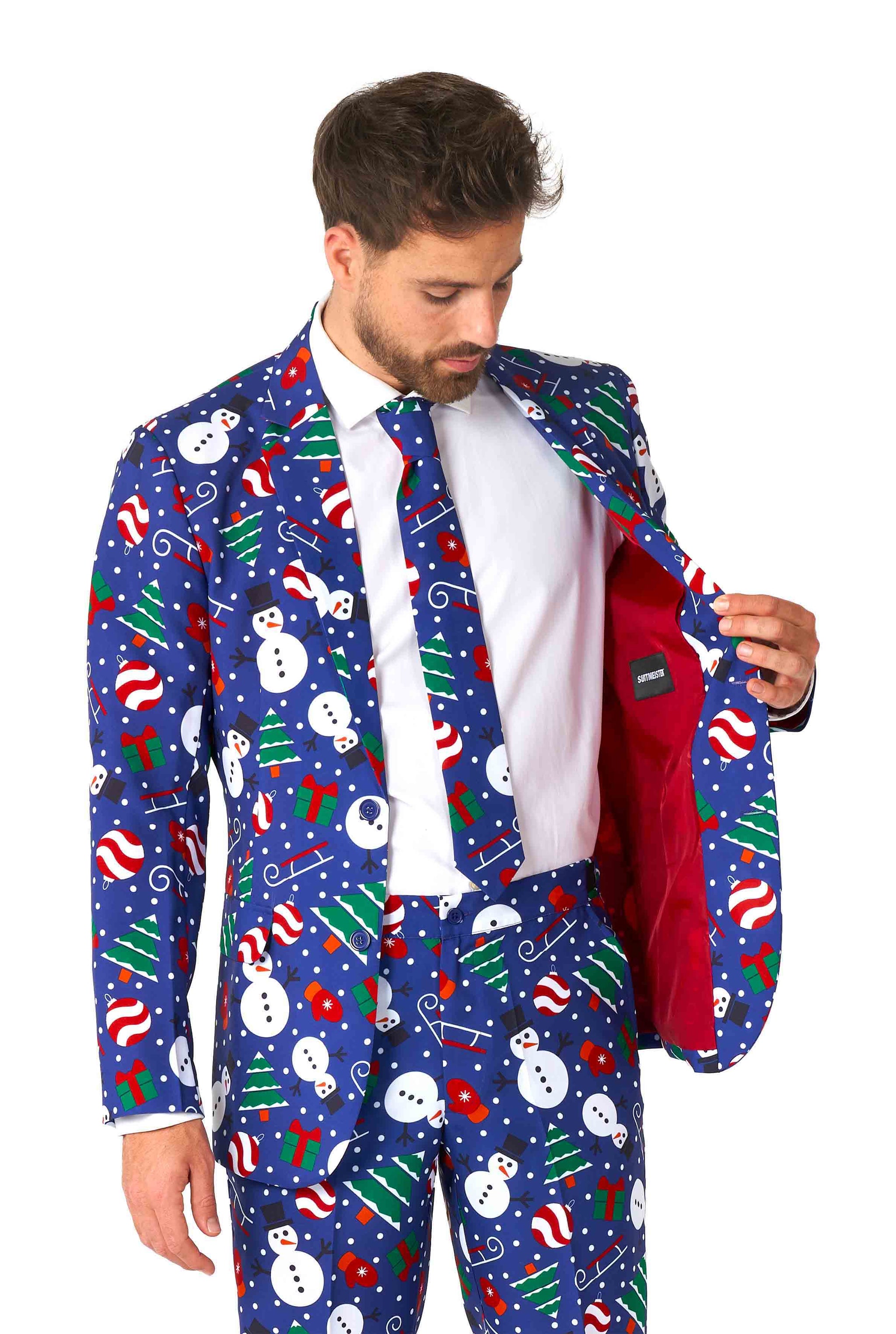 A man dressed in the Suitmeister "Christmas Snowman Blue" ensemble, adorned with snowmen, candy canes, and Christmas trees on a blue backdrop. The suit comes with a coordinated tie, and he is examining the red lining of the jacket.