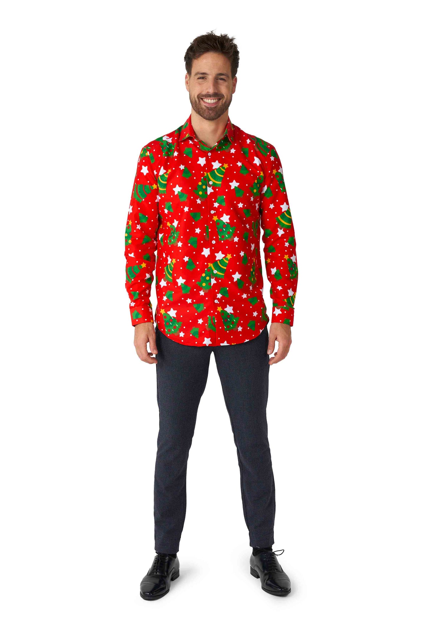 A man stands smiling, wearing the Suitmeister "Christmas Trees Stars Red" shirt adorned with green Christmas trees and white stars. He pairs it with dark pants and black shoes, standing against a plain white background.