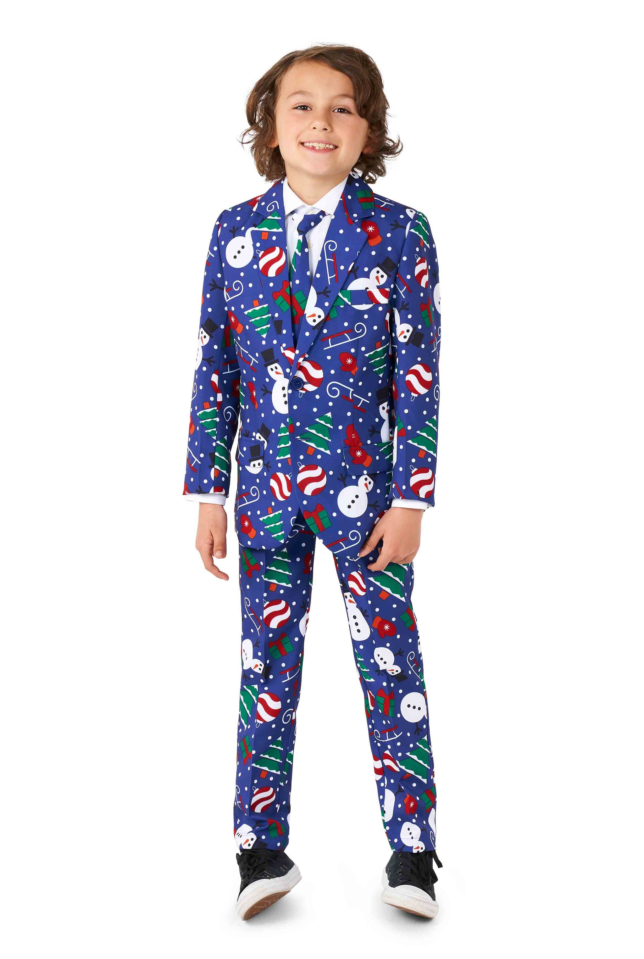 A cheerful child dressed in Suitmeister's Christmas Snowman Blue suit, featuring festive patterns of snowmen, candy canes, and ornaments. The child stands confidently in casual sneakers.