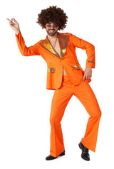 A person wearing the Suitmeister Disco Suit Orange, embellished with sequined accents, dances energetically. They have curly hair and sunglasses, with a playful expression as they strike a dynamic pose with one arm pointed upward against a plain white background.