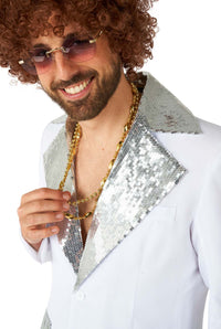 A person wearing a Disco Suit White by Suitmeister, featuring silver sequin lapels, sunglasses, a curly wig, and a gold chain, smiles at the camera.