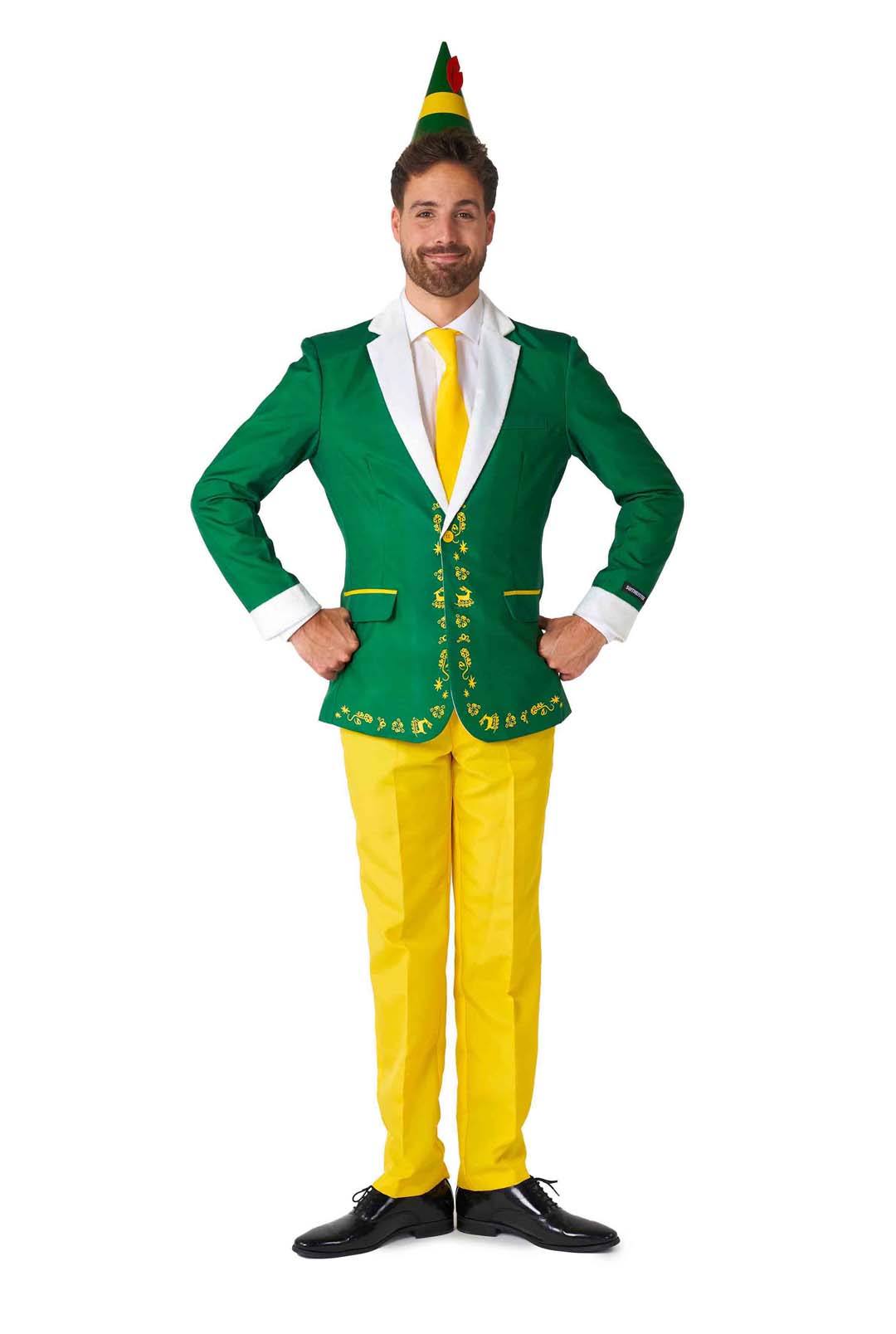 A man dressed in the Suitmeister's Elf™ - Christmas Suit Elf dons a green jacket adorned with yellow floral designs, paired with yellow pants, a white shirt, and a coordinating yellow tie. Completing the look is his green elf hat featuring a red feather. He stands confidently with hands on hips and smiles broadly.