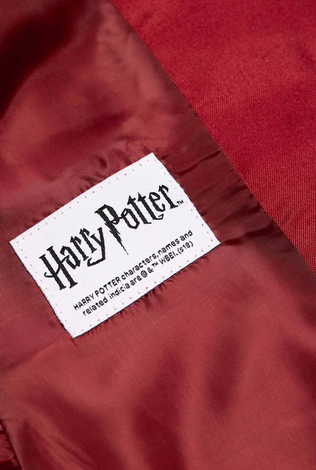 A close-up of a red fabric displaying a white label. The label showcases the text "Harry Potter" in a stylized font, with supplementary small print below regarding trademarks. This is from the Harry Potter Gryffindor™ Blazer by Suitmeister.