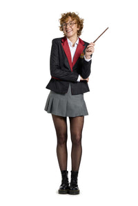 A person with curly hair stands smiling, wearing glasses, a Suitmeister Harry Potter Gryffindor™ Blazer with red accents, a white shirt, a gray pleated skirt, and black boots. They hold a wand in their right hand against a white background.