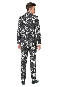 A person dressed in the "Halloween Black Icons" suit by Suitmeister is featured. The Halloween pattern on their black and white attire includes skulls, ghosts, and spiderwebs. They are facing away from the camera, showcasing matching pants and shoes against a plain white background.