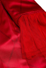 Close-up of the Harley Quinn™ by Suitmeister, featuring a vibrant red fabric with a silky texture and a pleated design. The pleats add depth and contrast to the smooth, luminous surface, creating an elegant, layered effect.