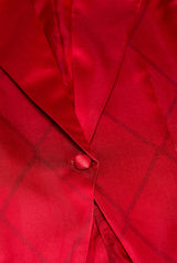 Close-up of the vibrant red Harley Quinn™ jacket by Suitmeister, featuring a subtle check pattern. The image highlights the fabric texture and a prominent round button on the front.