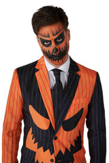 A person dressed in Suitmeister's "Jack-O Pinstripe Black" suit, featuring black and orange stripes with a pumpkin face design. Their face is painted like a jack-o-lantern, showcasing dark eyes, a nose, and a jagged mouth pattern. A black tie completes this Halloween-themed ensemble.