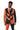 A man is dressed in the Jack-O Pinstripe Black Halloween suit from Suitmeister, featuring orange and black vertical stripes and a stylized pumpkin face design. His face is painted with orange and black makeup to resemble a jack-o-lantern.