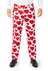 A person dressed in the Love - Heart suit by Suitmeister, featuring white pants adorned with large red hearts, complemented by a white shirt and black shoes, stands against a white background.