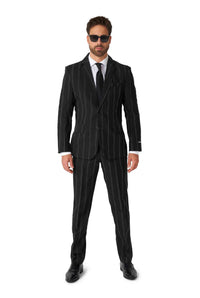 A man stands confidently wearing the Suitmeister Oversized Pinstripe Black suit, complemented by a crisp white shirt, a sleek black tie, and matching black shoes. He completes his look with stylish sunglasses against a plain white background.