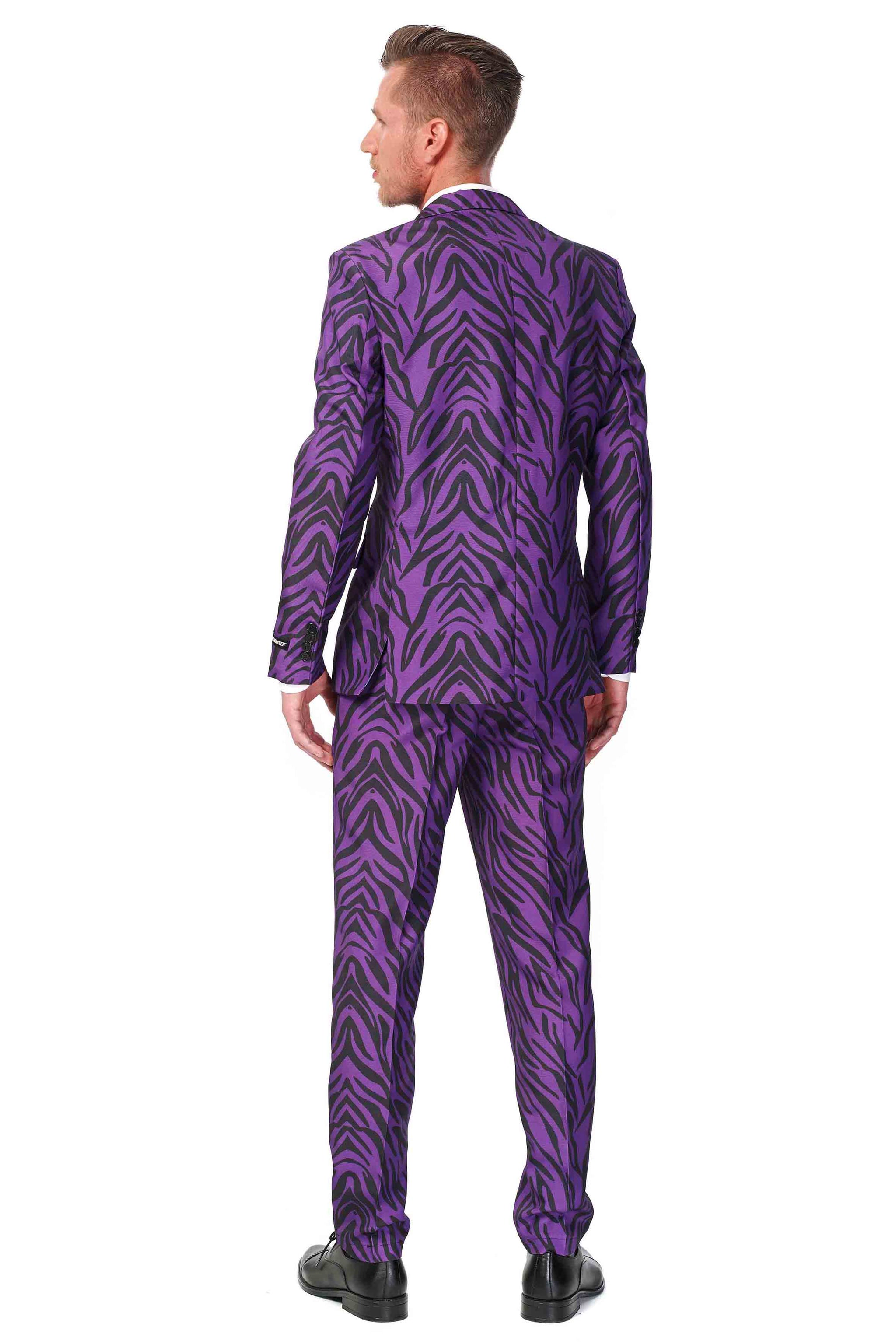 A man stands with his back to the camera, donning the Suitmeister "Pimp Tiger" suit, featuring a striking vibrant purple hue blended with a bold black tiger stripe pattern. He sports short hair and pairs the ensemble with sleek black shoes against a plain white backdrop.