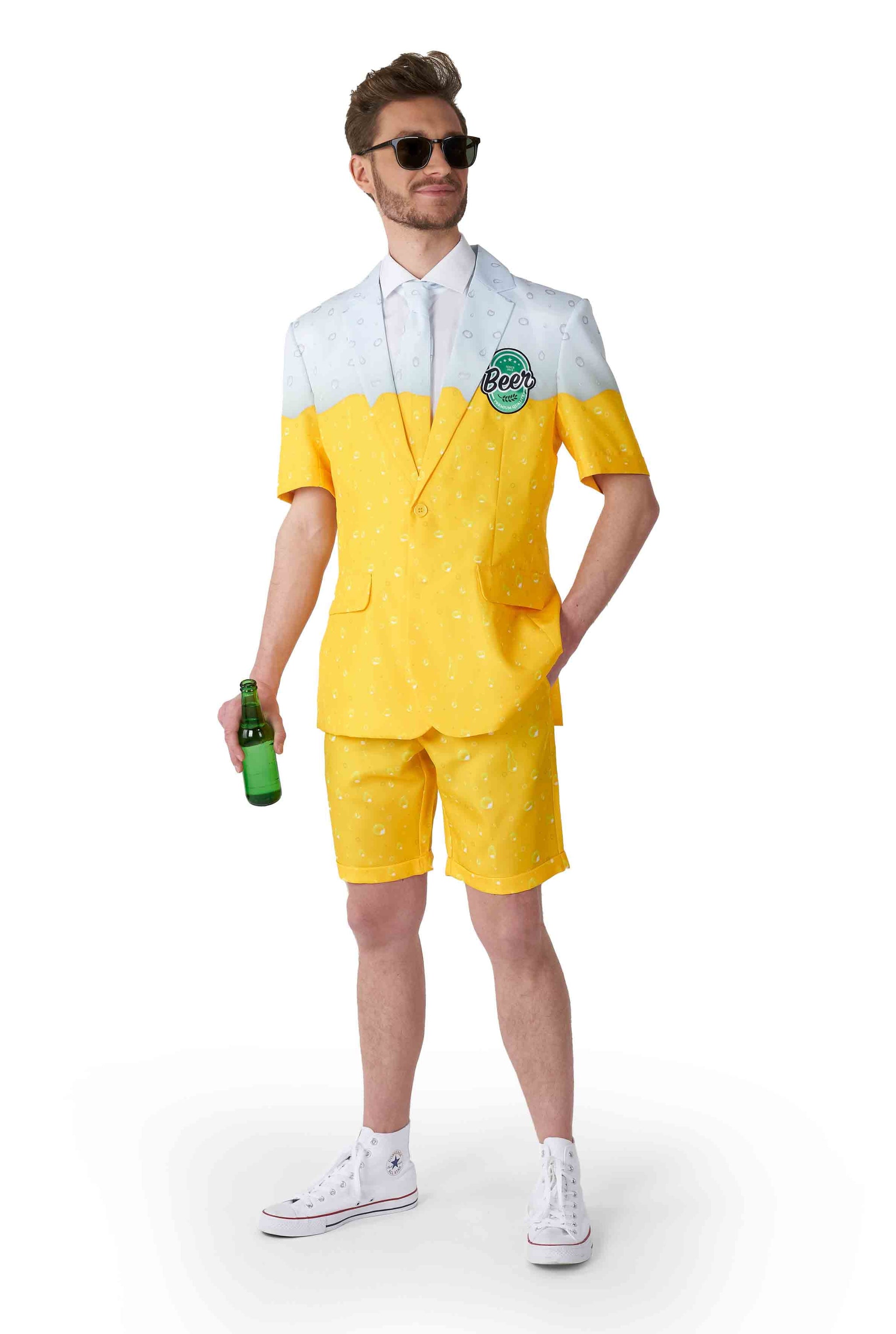 A person is sporting a Suitmeister Premium Beer Yellow novelty suit, featuring a short-sleeved blazer and matching shorts with a design reminiscent of a beer mug. They are holding a green bottle and wearing sunglasses.