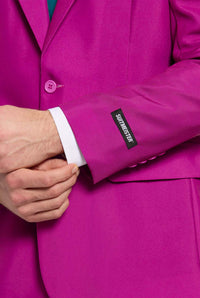 A person wearing a vibrant suit adjusts their sleeve, and the label on the sleeve reads Suitmeister. They also have a white shirt underneath, and their hand is slightly visible.