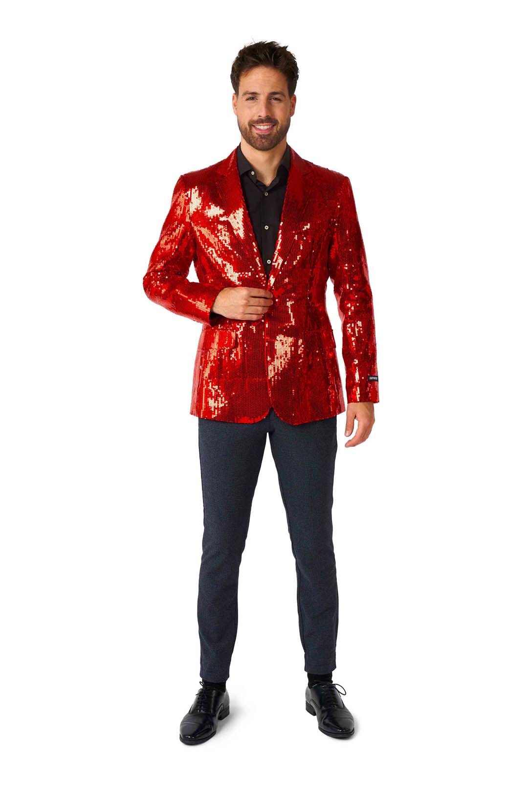 A man stands confidently against a white background, donning the vibrant Sequins Blazer Red by Suitmeister, complemented by a black shirt, dark pants, and sleek black shoes.