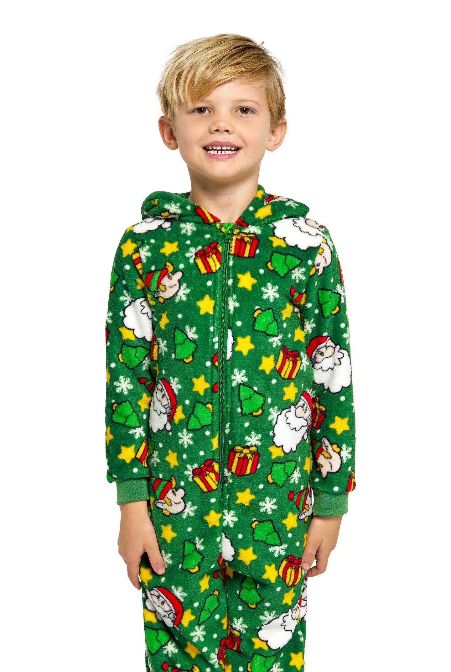 A cheerful child wearing the Suitmeister Santa Elves Green onesie, adorned with festive patterns such as Santa faces, sheep, presents, stars, and snowflakes, stands against a white background.