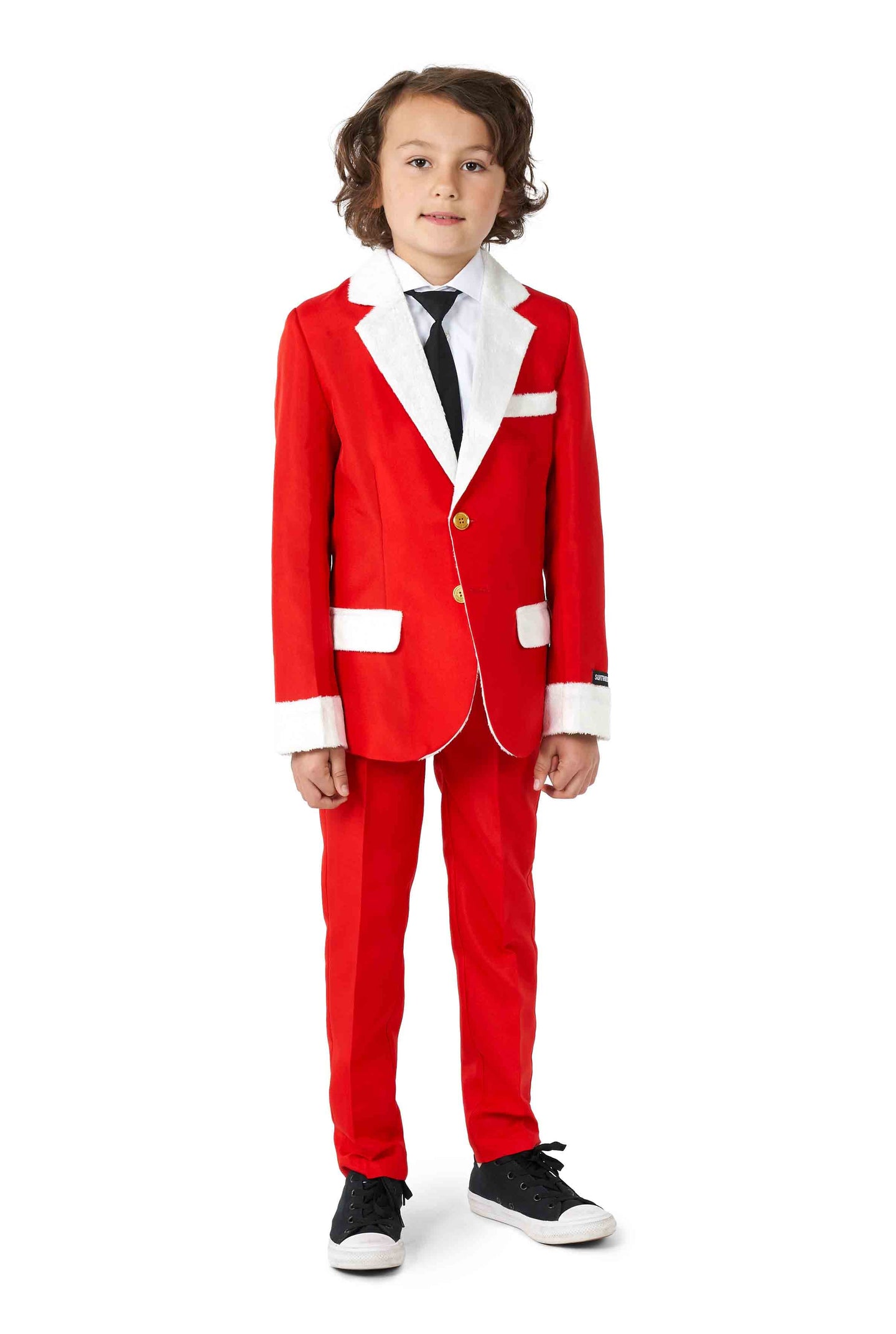 A young boy dressed in the Suitmeister's "Santa Faux Fur - Christmas suit," complete with white trim, a black tie, and black sneakers, stands against a white background.