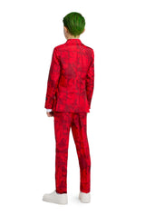 A person with green hair is shown from the back, wearing Suitmeister's Scarlet Joker, a vibrant red suit adorned with graphic patterns, complemented by white sneakers. The white background accentuates the bold colors of their ensemble.