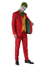 A person dressed in the Scarlet Joker™ from Suitmeister, featuring a red suit adorned with black patterns, complemented by a yellow vest and a green shirt. Their face is painted with a clown-like design, and they have green hair. They are holding one side of the jacket open to reveal its green lining.