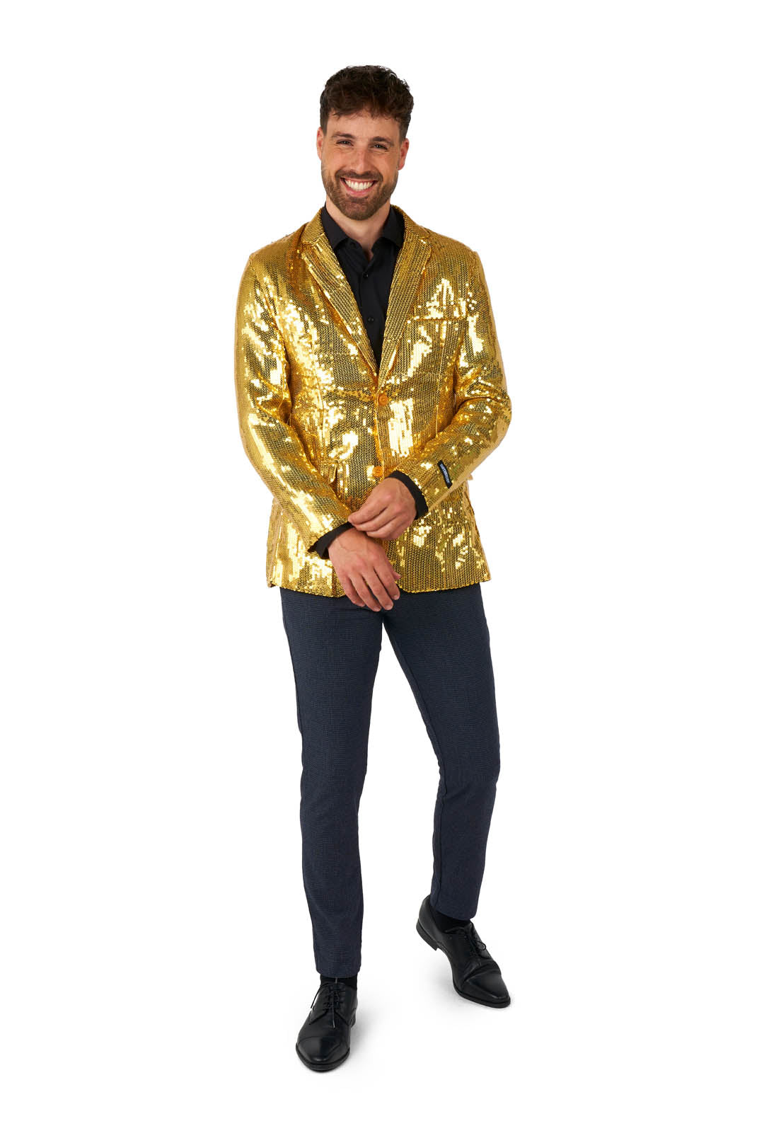 A man wearing a Suitmeister Sequins Blazer Gold, paired with a black shirt and dark pants, poses confidently. He stands against a white background, smiling and clasping his hands.