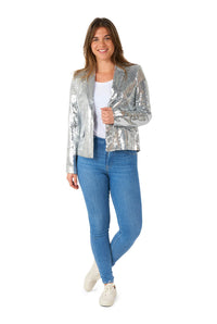 A woman stands smiling, wearing the Sequins Silver - Sequin blazer by Suitmeister over a white top, paired with blue jeans and white sneakers. She poses against a plain white background.