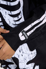 A close-up showcases an individual dressed in Suitmeister's Skeleton Grunge Black hoodie, adorned with a distressed white skeleton design, while the SOUTHFRESH label is visible on the sleeve. The person has their hand resting on their hip.