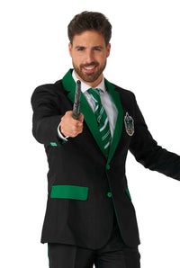 A man dressed in the Suitmeister Harry Potter - Slytherin™ ensemble is wearing a black and green suit adorned with an emblem on the chest, complemented by a green and white striped tie. He has facial hair, is smiling while holding a wand, and is posing against a white background.