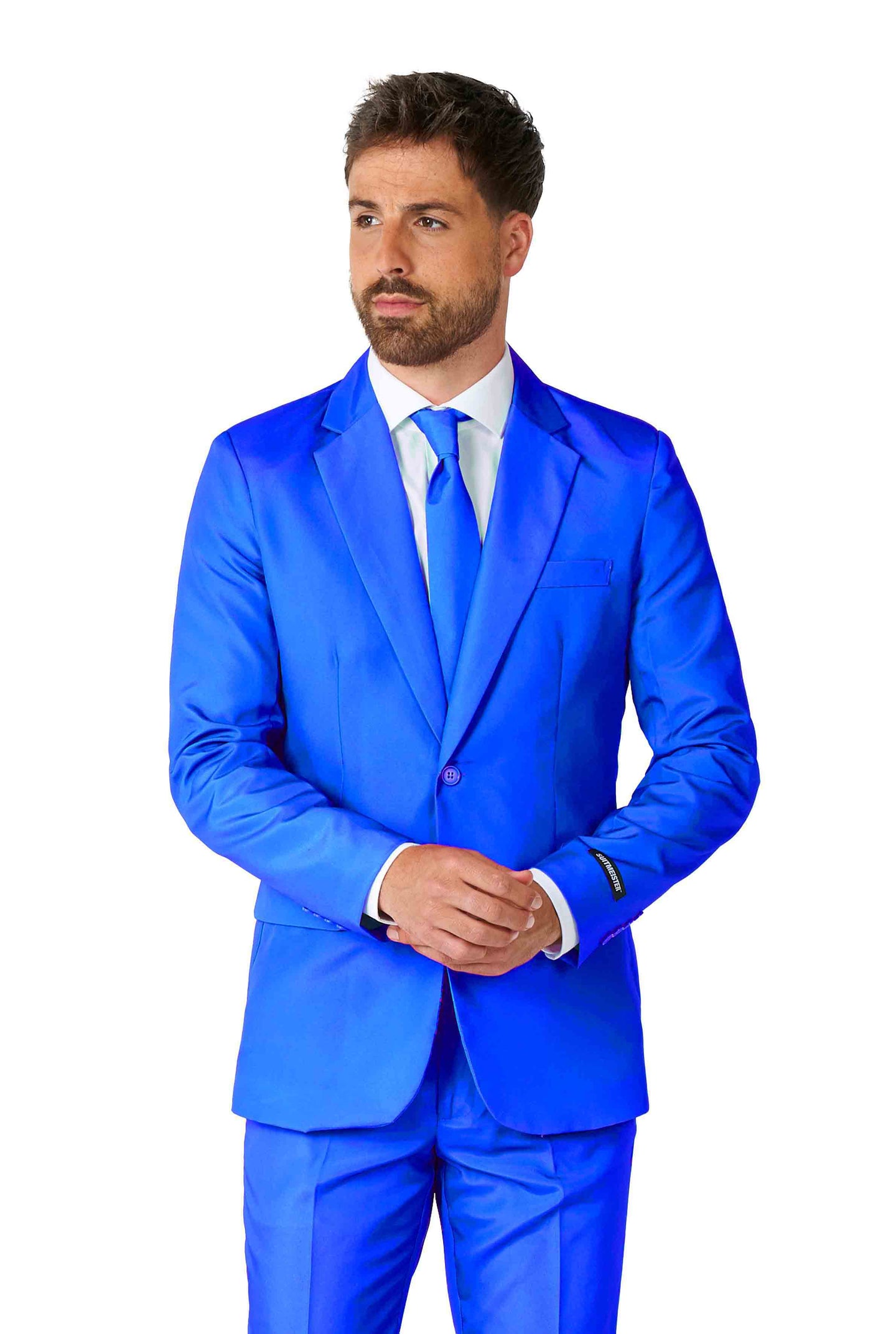 A person wearing the Solid Blue suit from Suitmeister, along with a white shirt and matching blue tie, stands with hands clasped against a plain white background.