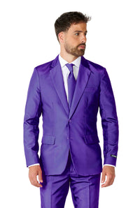 A man wearing the Suitmeister "Solid Purple" suit, complete with a matching tie and crisp white dress shirt. The suit jacket is buttoned up as he stands against a plain white background, gazing to his right.