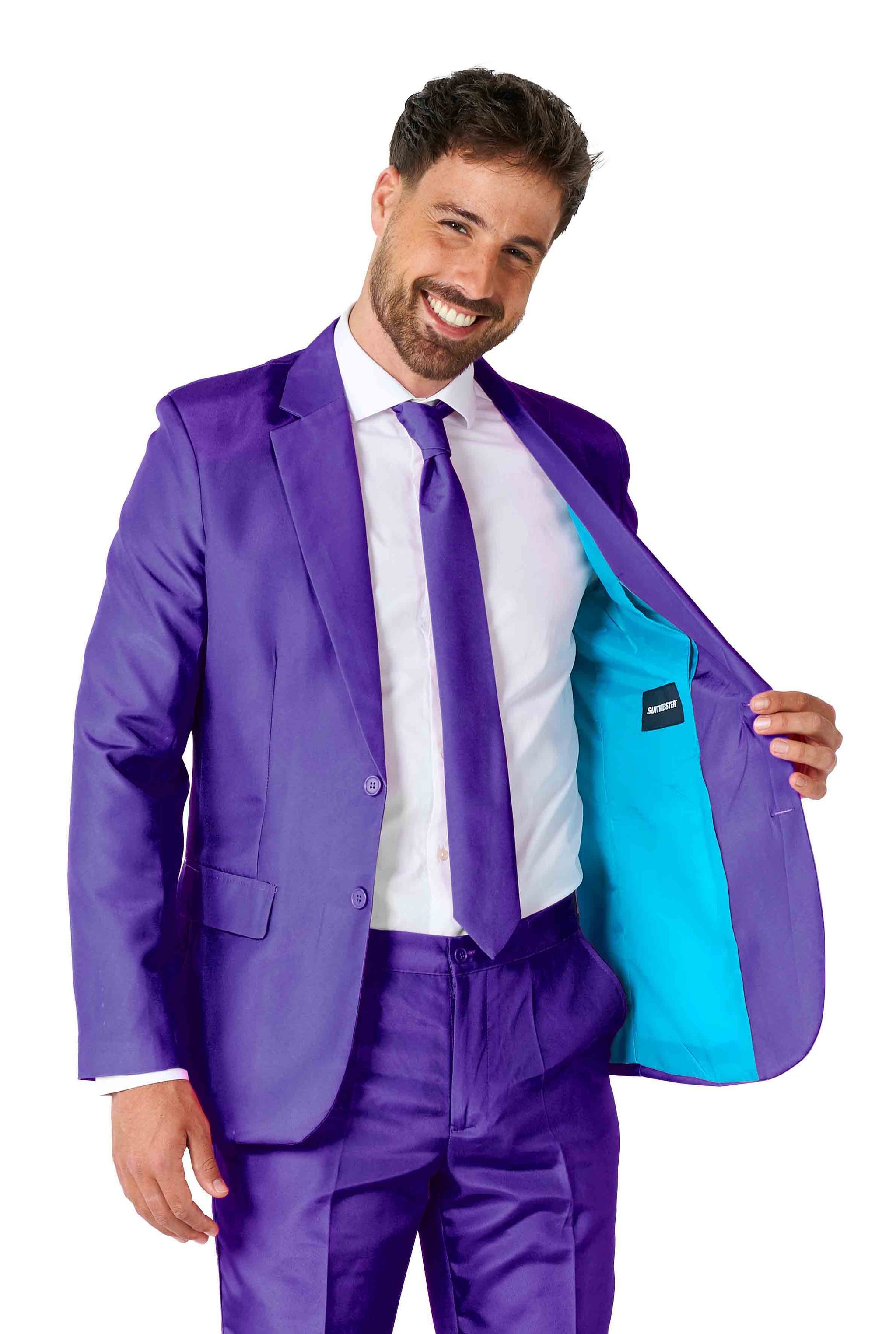 A man smiling, dressed in a Solid Purple suit from Suitmeister with a matching tie, is holding open his jacket to reveal its bright turquoise lining. The background is plain white.