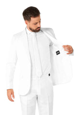 A man wearing the Solid White suit from Suitmeister inspects the inside of his jacket, adjusting it while its tag is visible. The backdrop is a plain white.