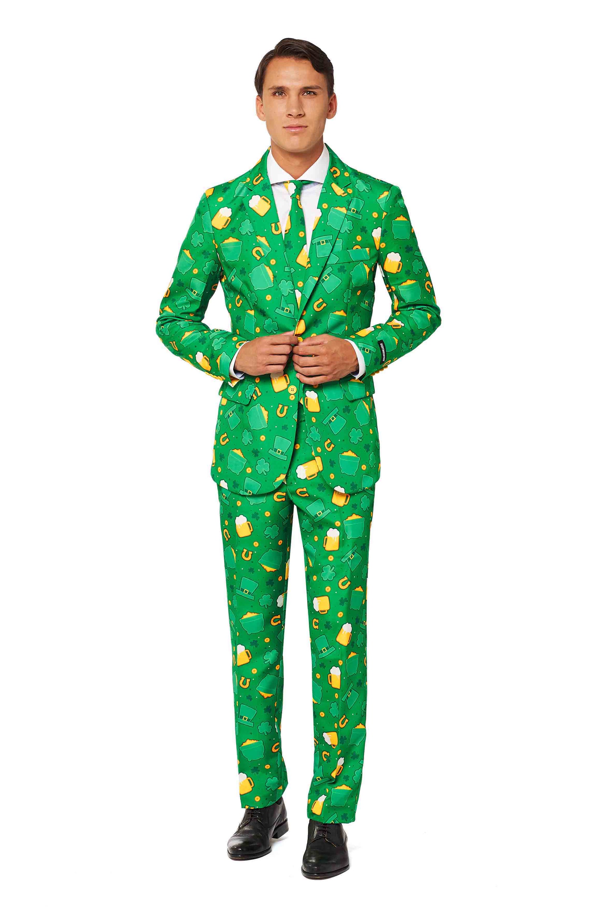 A person stands wearing the Suitmeister St. Patrick's Day Icons suit, featuring a vibrant green design adorned with bold yellow beer mugs and shamrocks. The ensemble includes a matching tie and a crisp white shirt, while they stand on a white background sporting black shoes.