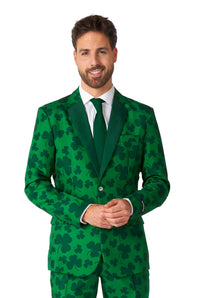 A man dressed in the Suitmeister St. Pats Green - St Patrick's Day suit is standing and smiling. He pairs it with a white shirt and a green tie, with his hands clasped in front against a plain white background.